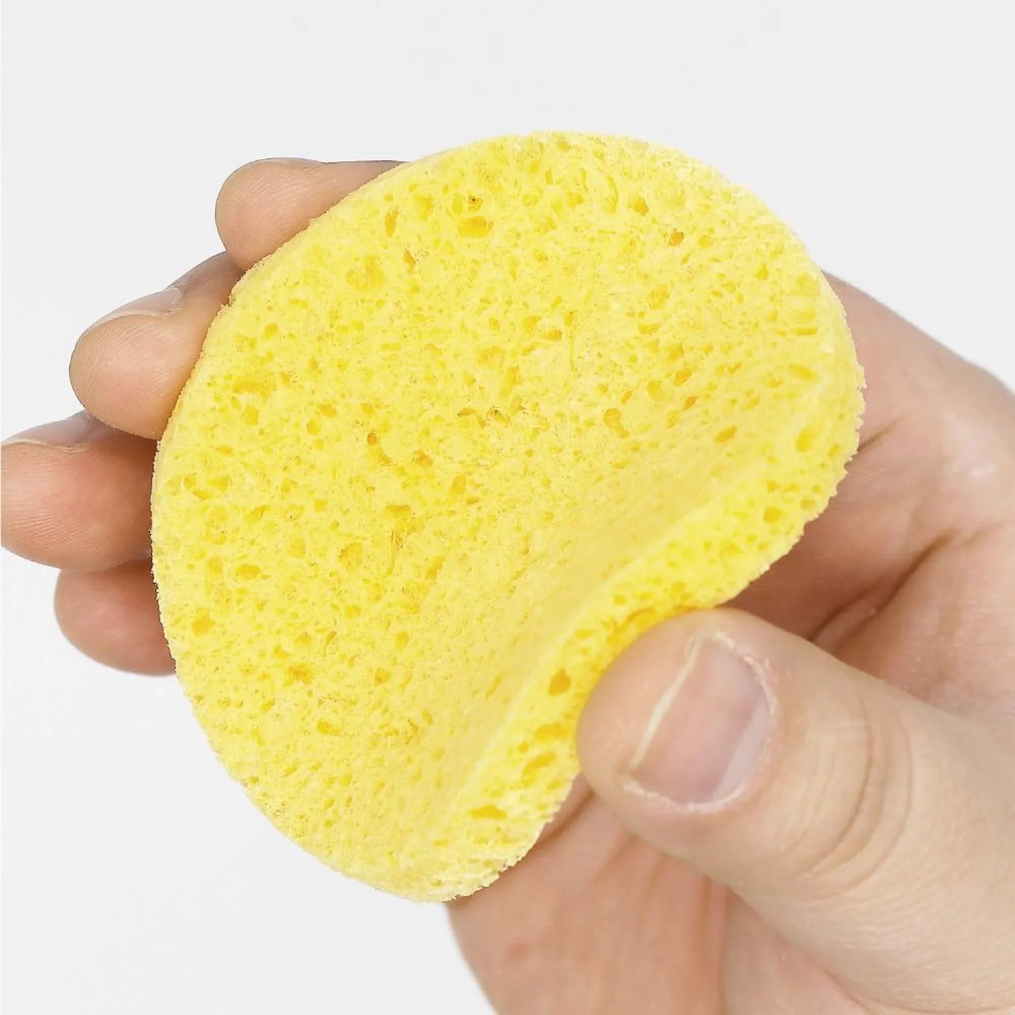 Hand holding a yellow sponge against a white background