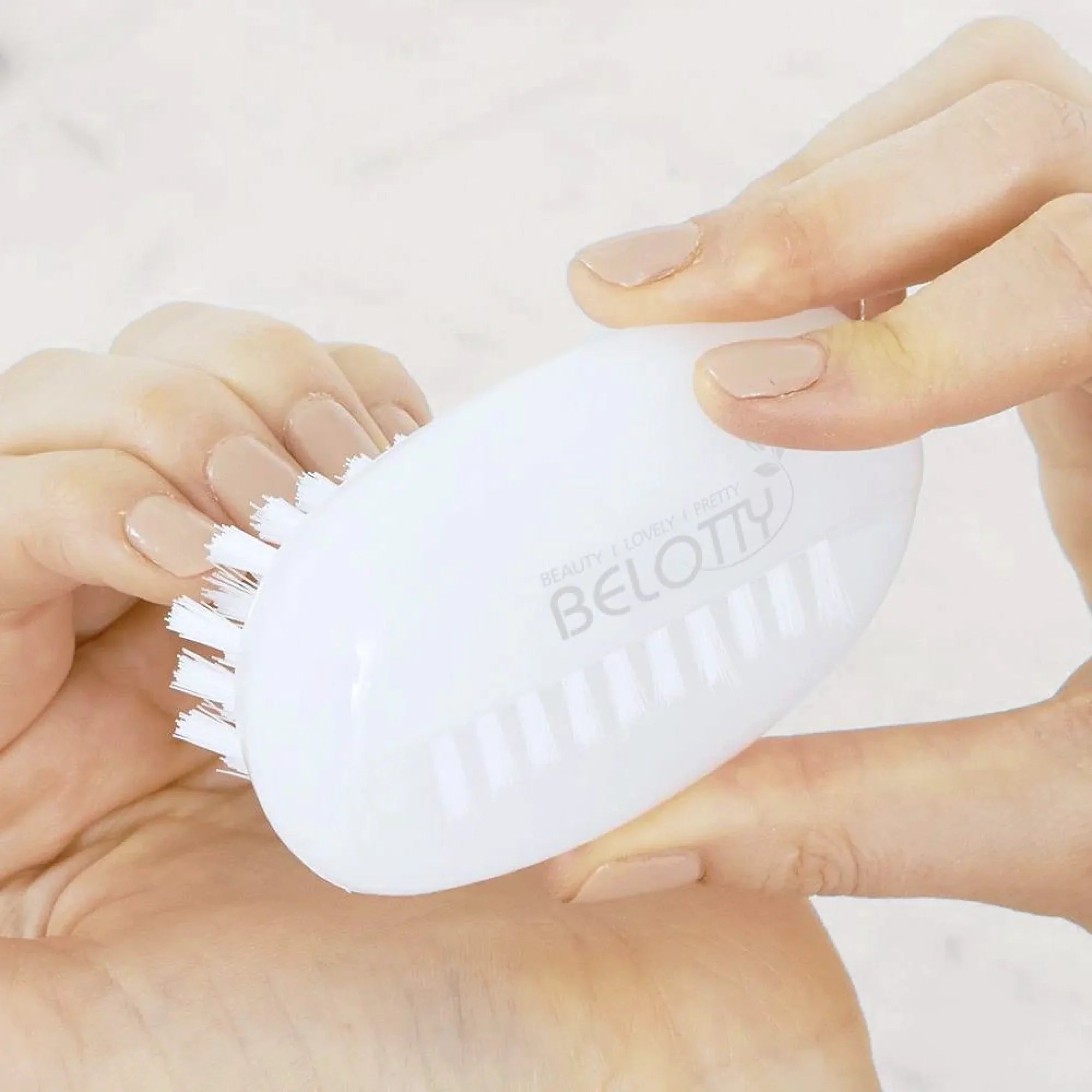 White brush by hands against a light back