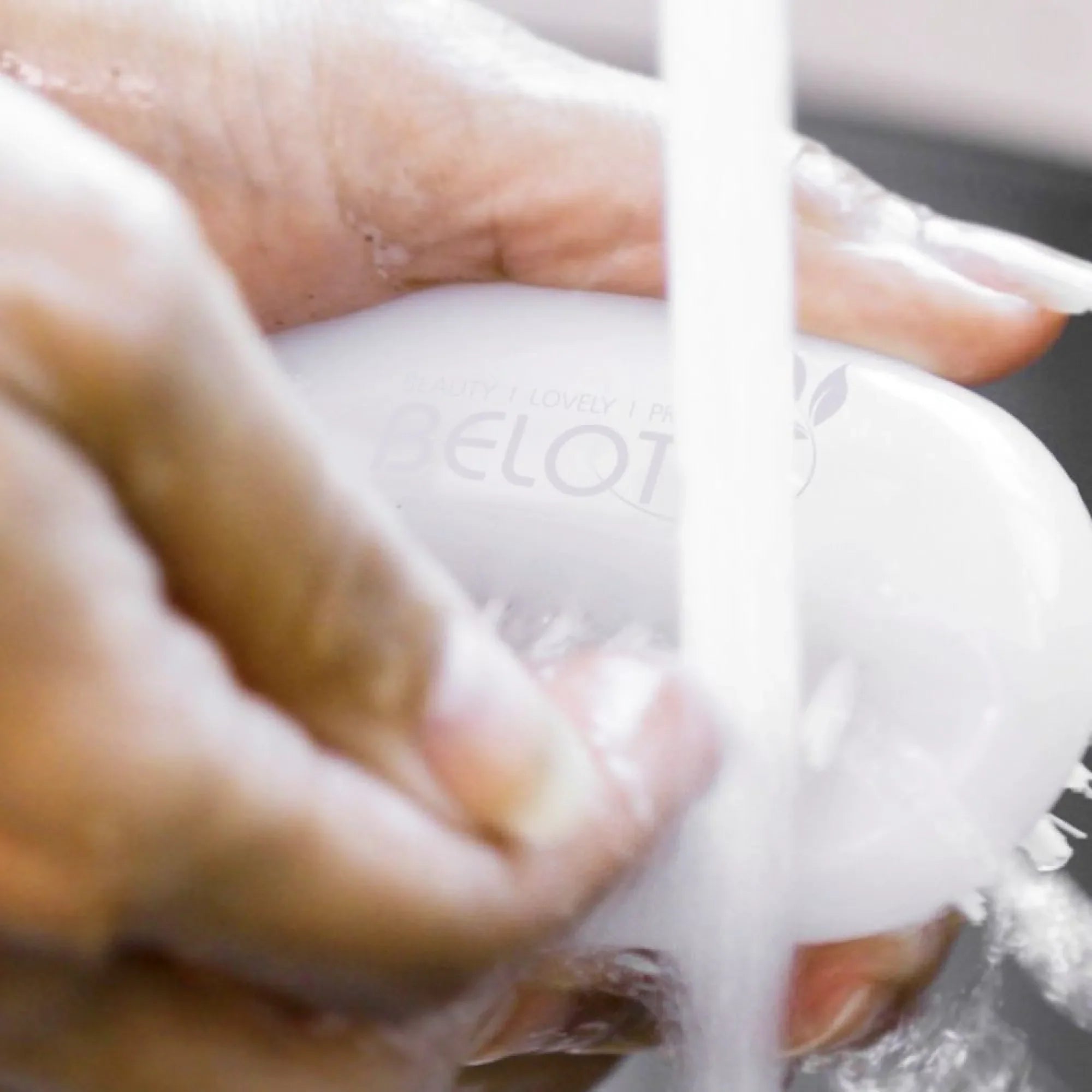Person washing a white brush with water, close-up view.
