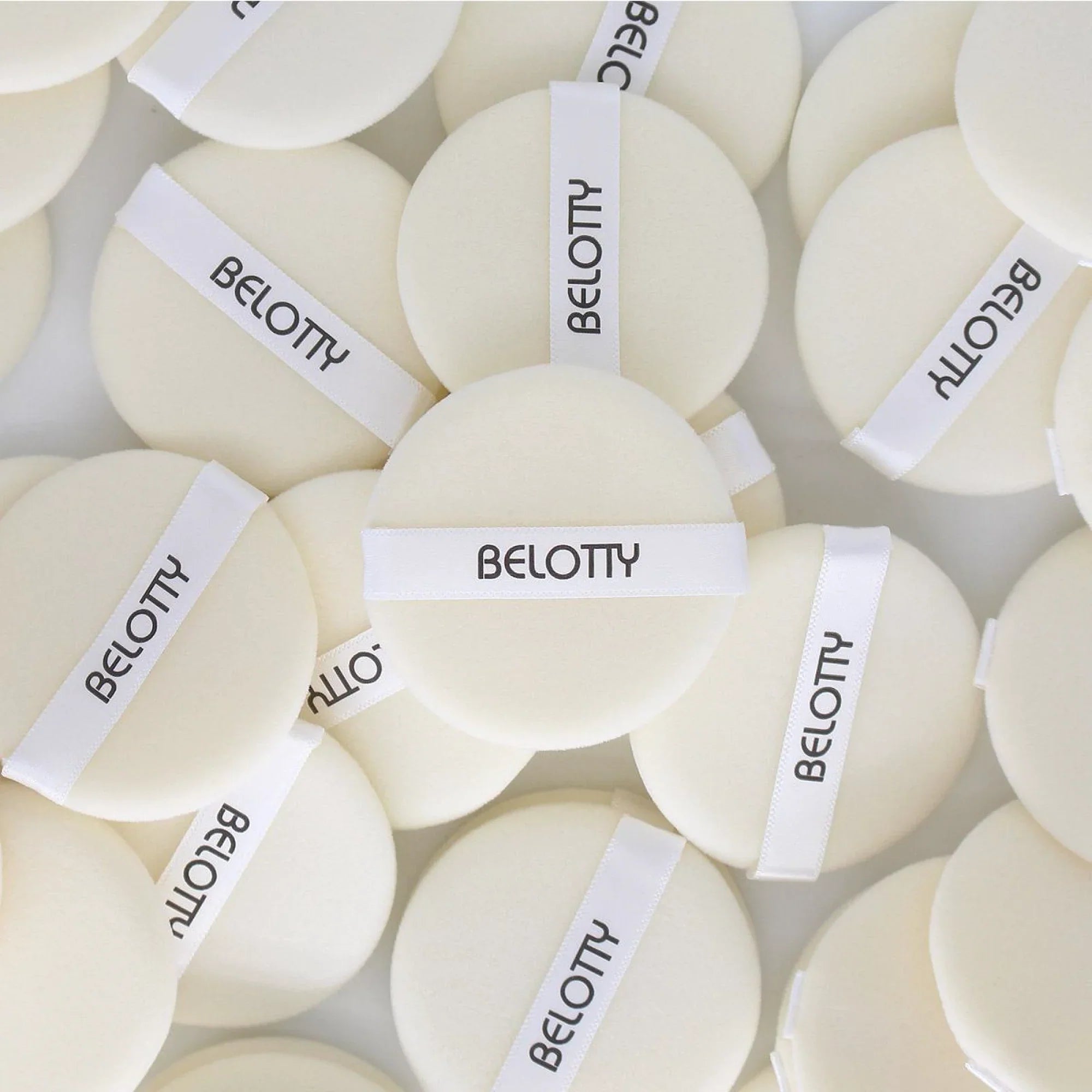 Multiple white bath bombs with 'BELOTTY' labels on a light background