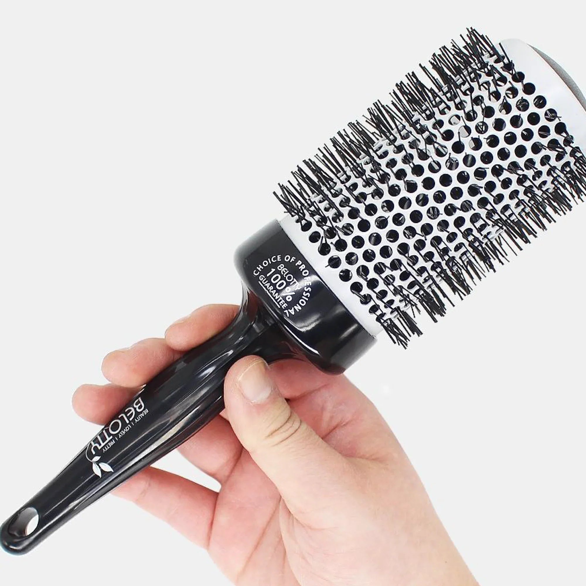 Hairbrush with black bristles held by a hand on a white background