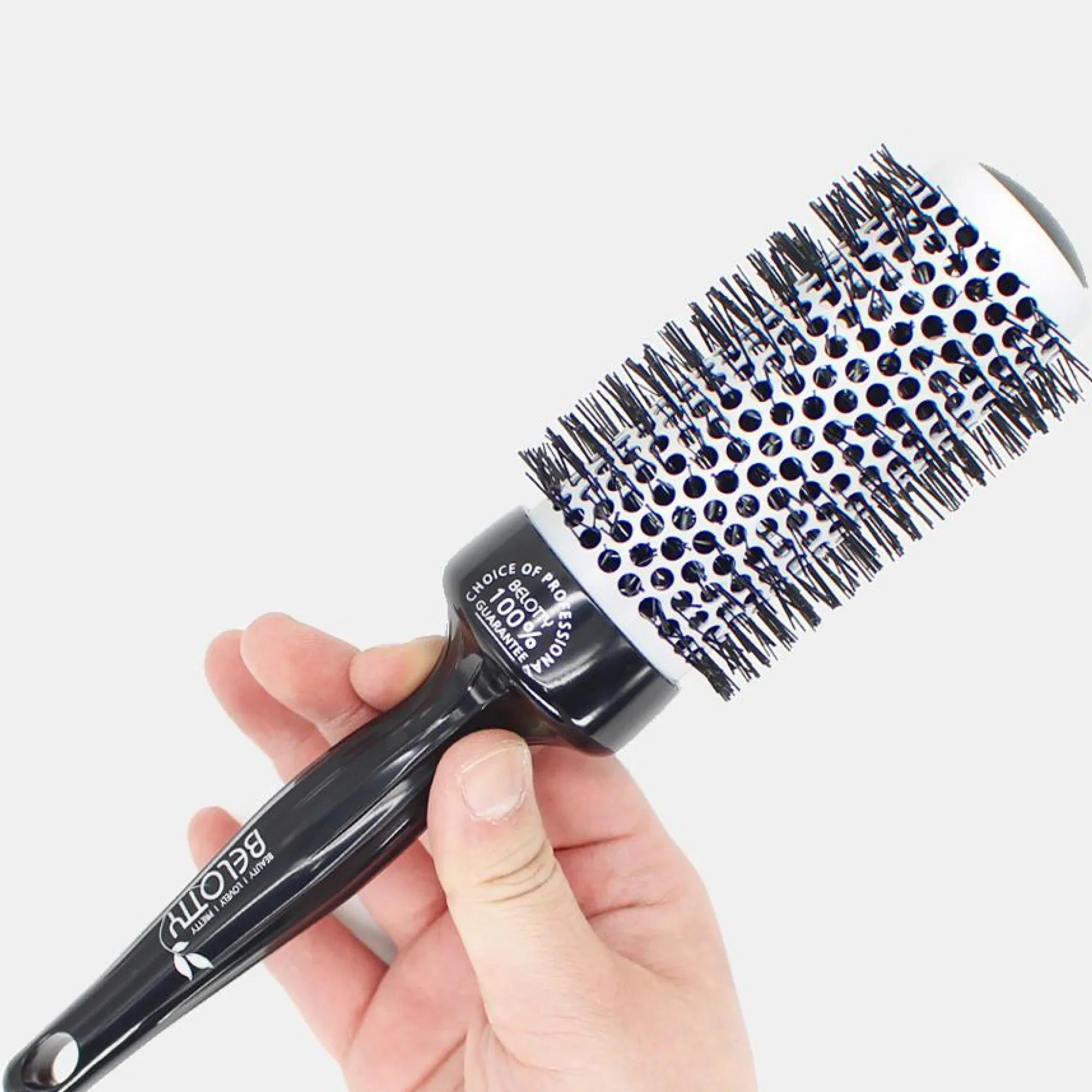 Black hairbrush with blue bristle tips held by a hand on a white background