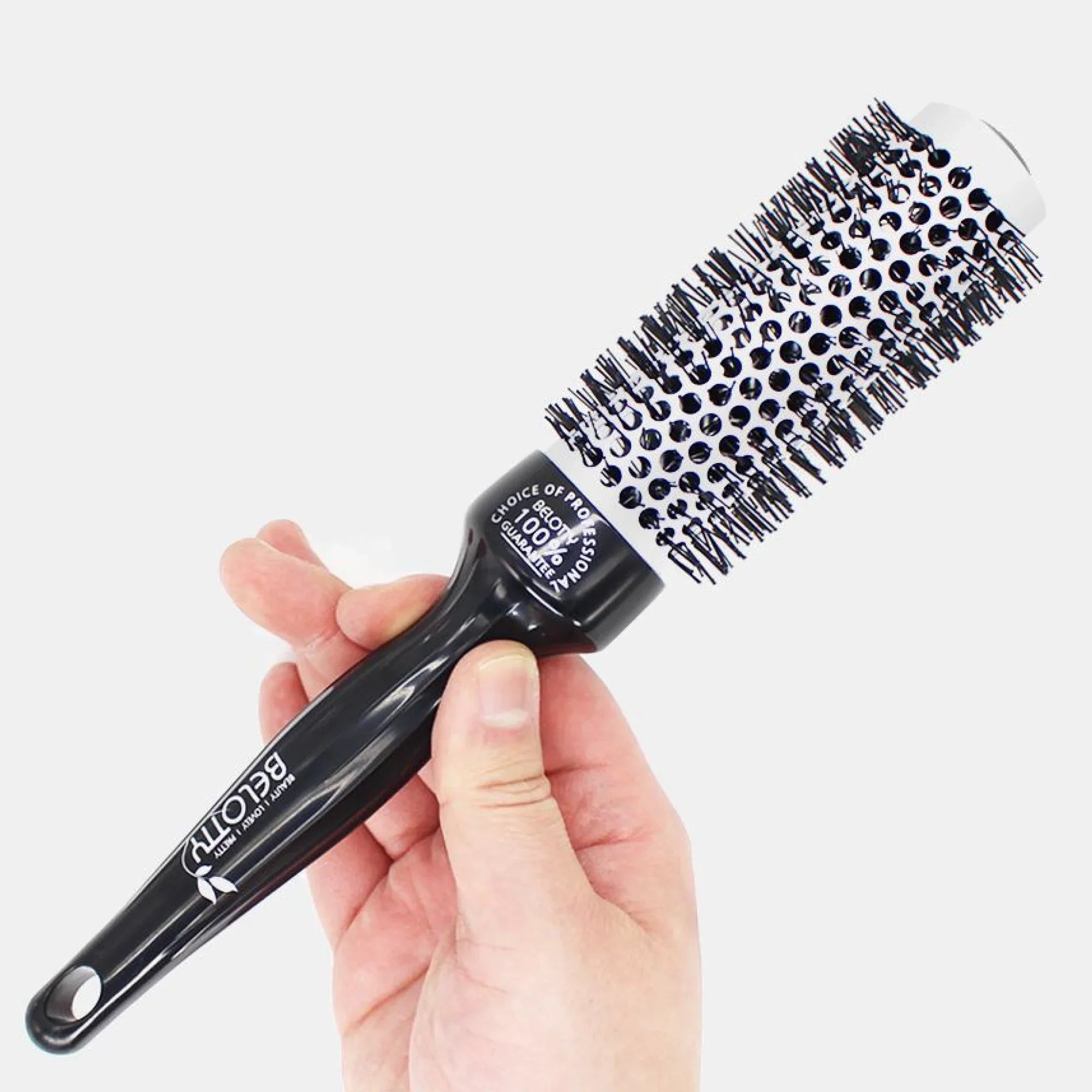 Black round hairbrush held in a hand against a white background