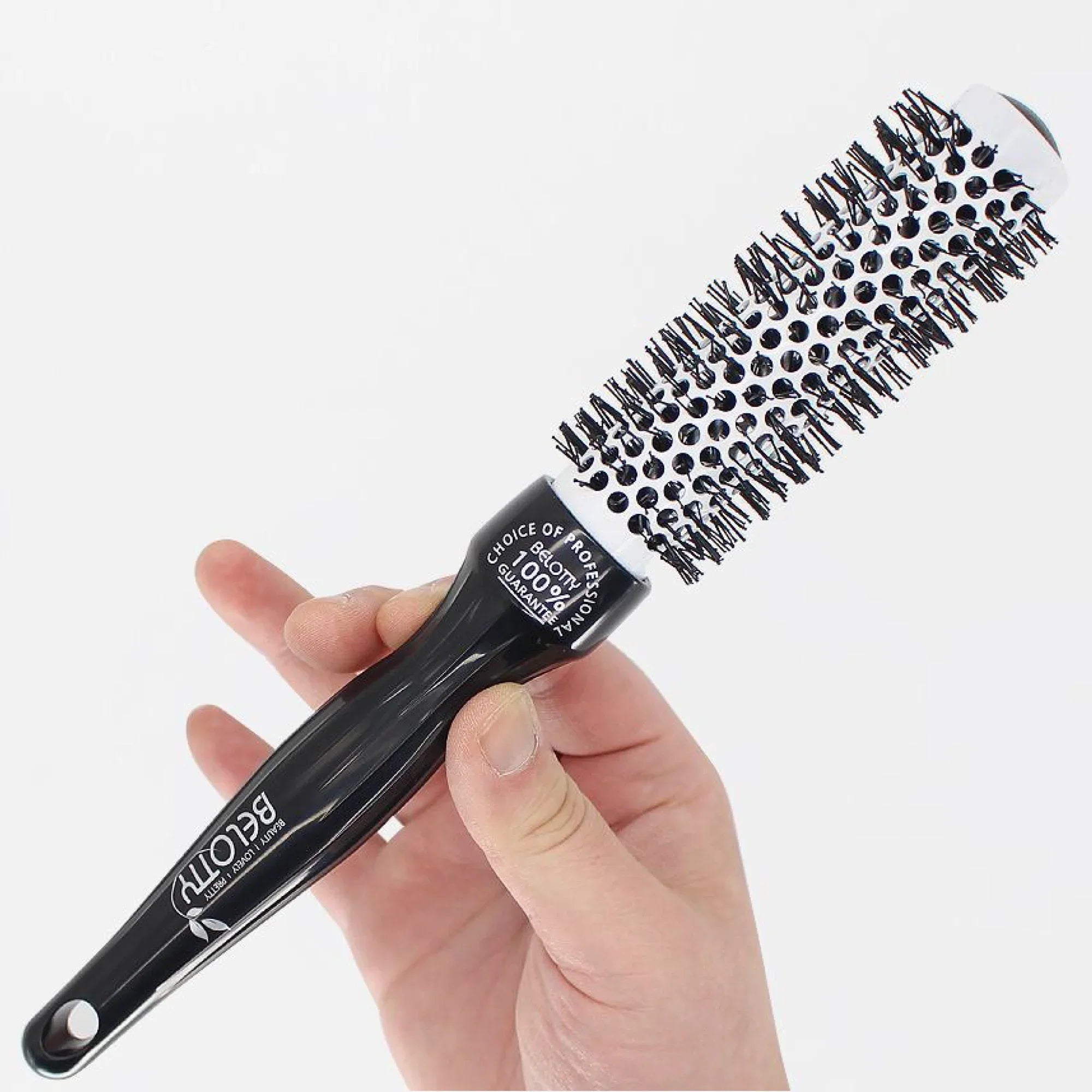 Black round brush held in a hand against a white background